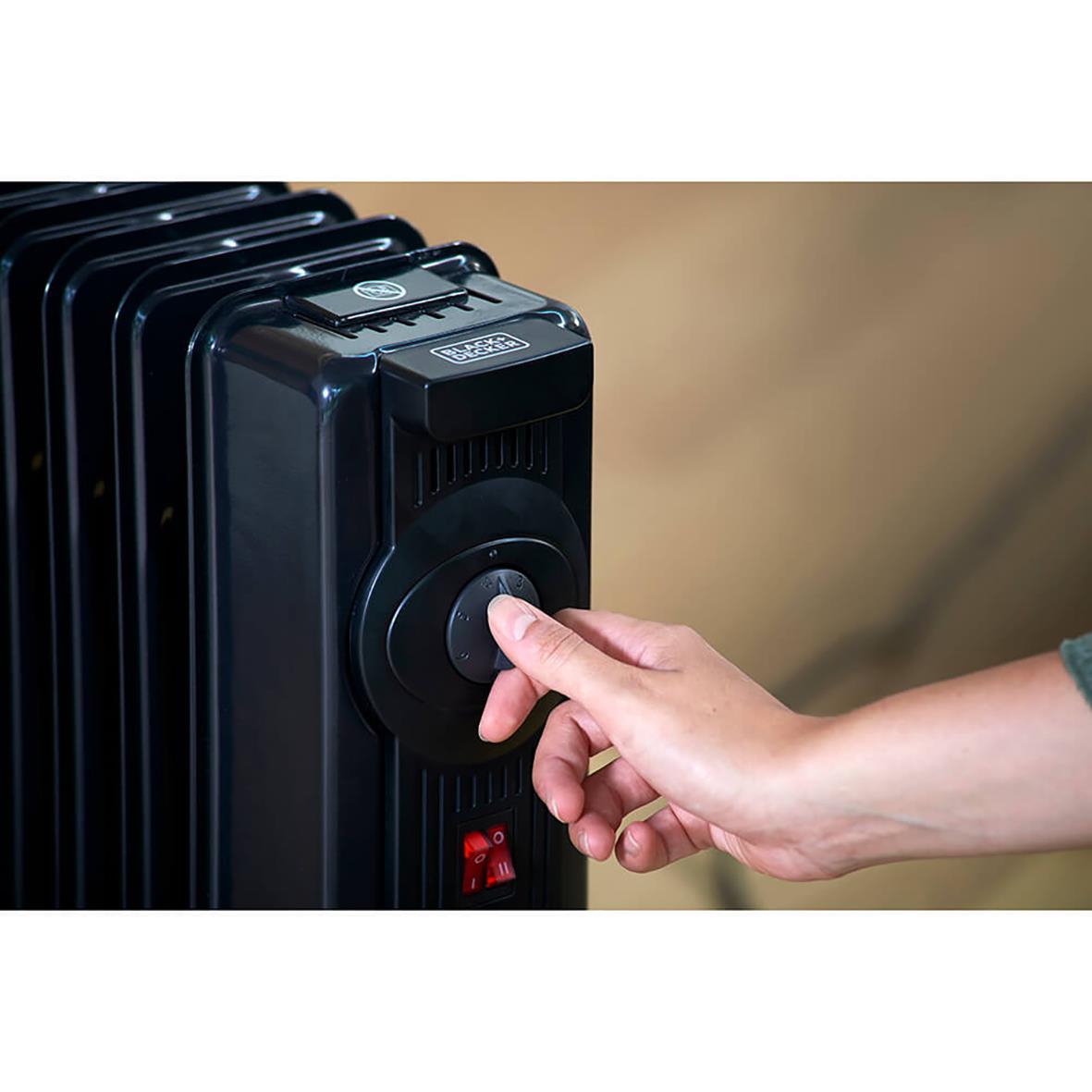 Hand som justerar en svart Element Black+Decker 2000W oljefylld radiator