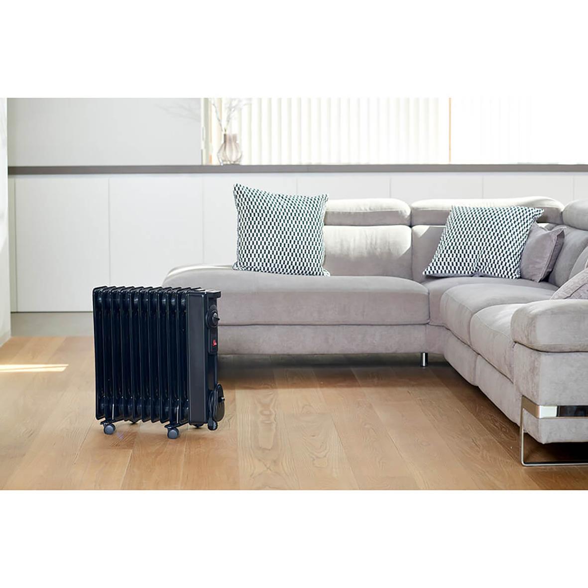 Svart oljefyllt Element Black+Decker 2000W radiator på trägolv i vardagsrum med soffa och kuddar