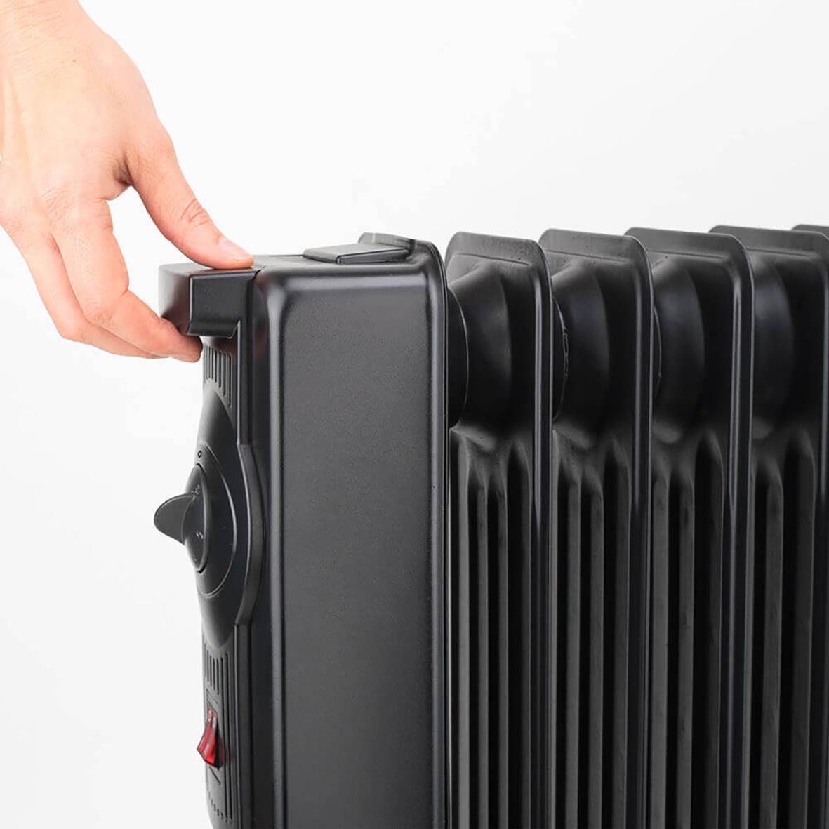 Hand som justerar en svart Element Black+Decker 2300W oljefylld radiator