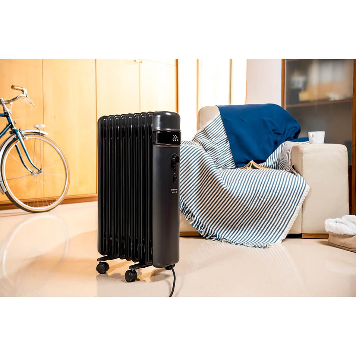 Element Taurus oljefyllt radiator i svart i ett vardagsrum med soffa, cykel och skåp
