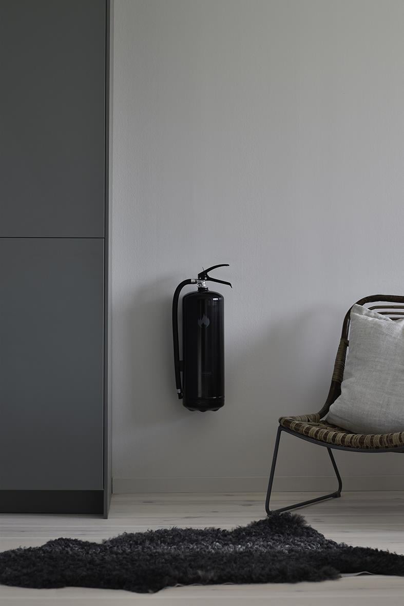 Svart brandsläckare Housegard Pulver 6kg på vägg bredvid stol och skåp