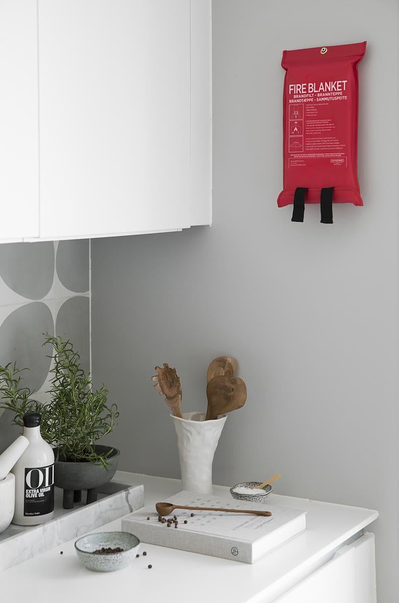 Röd brandfilt på vägg i kök, ovanför diskbänk med växt och köksartiklar