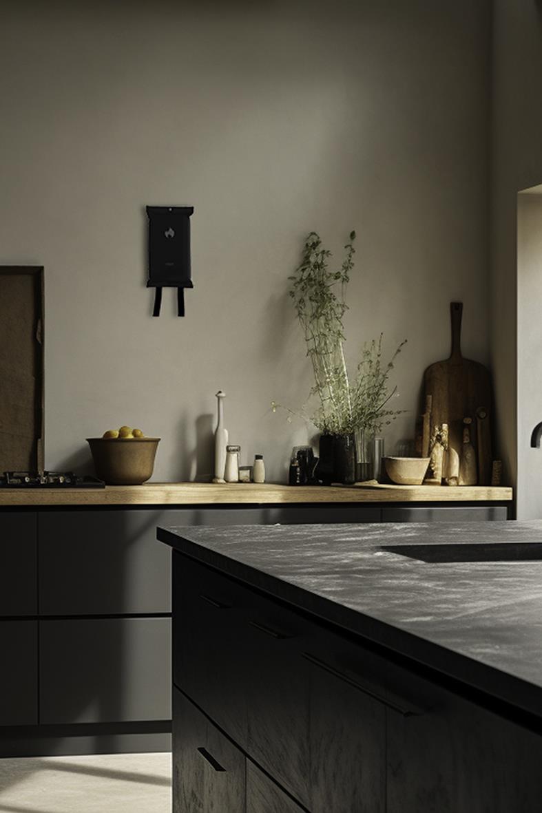 Kök med svart brandfilt på vägg, köksbänkar med skåp, växter och köksredskap i modern stil
