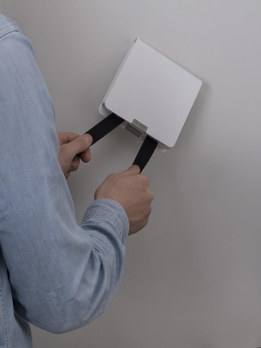 Person installerar en vit brandfilt i metallhölje på vägg