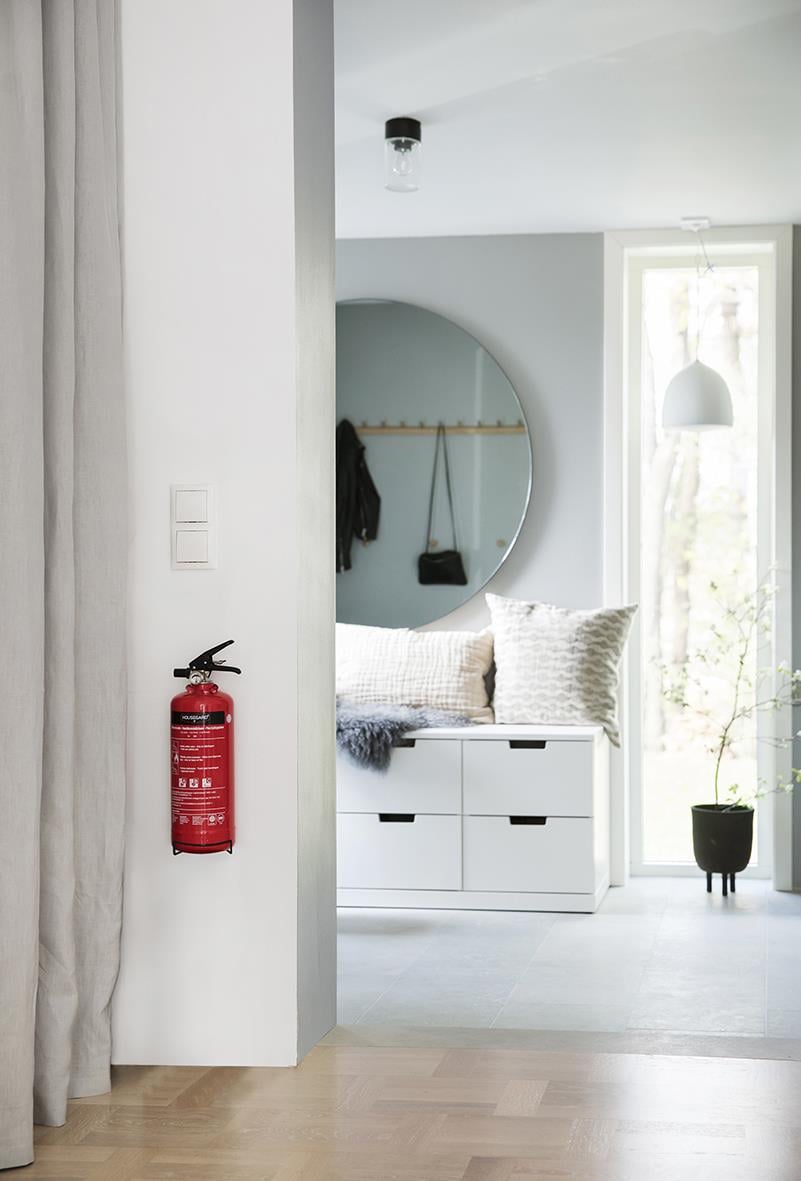 Röd brandsläckare Housegard Pulver 2kg monterad på vit vägg i ett hem