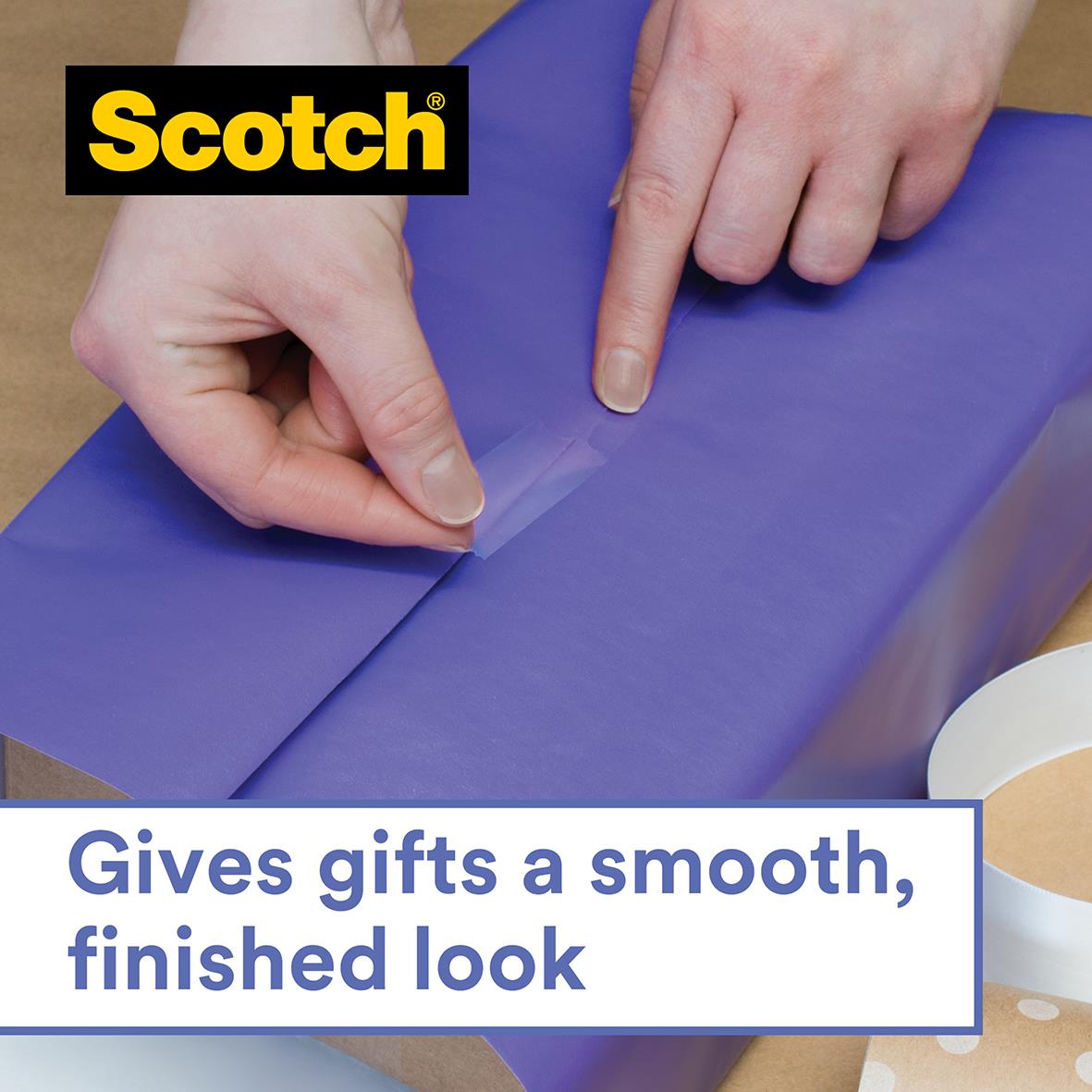 Person som använder transparent kontorstape för att slå in en present i blått papper