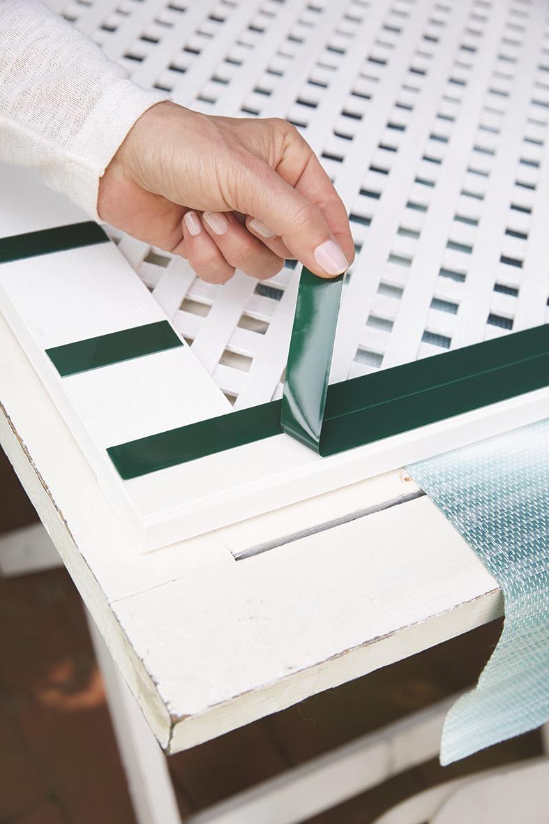 Person applicerar Tesa Powerbond utomhusmonteringstejp på en vit träyta