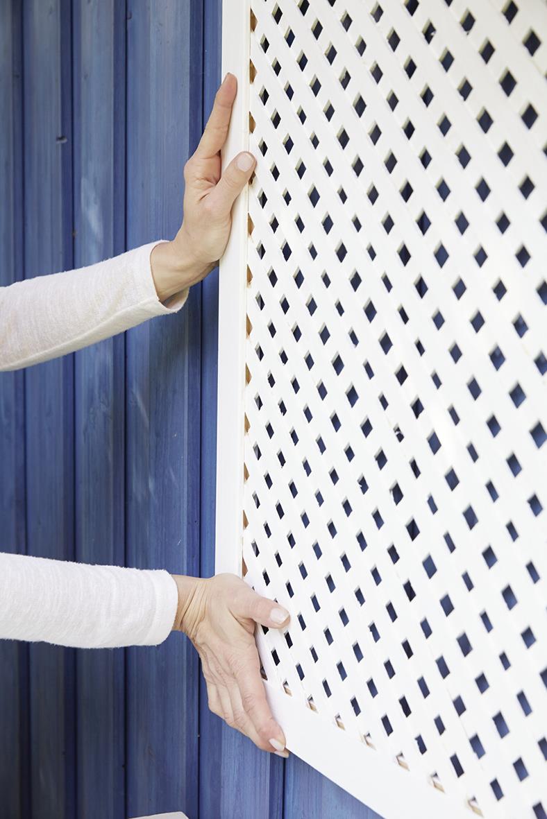 Person monterar Tesa Powerbond utomhustape på en vit träpanel