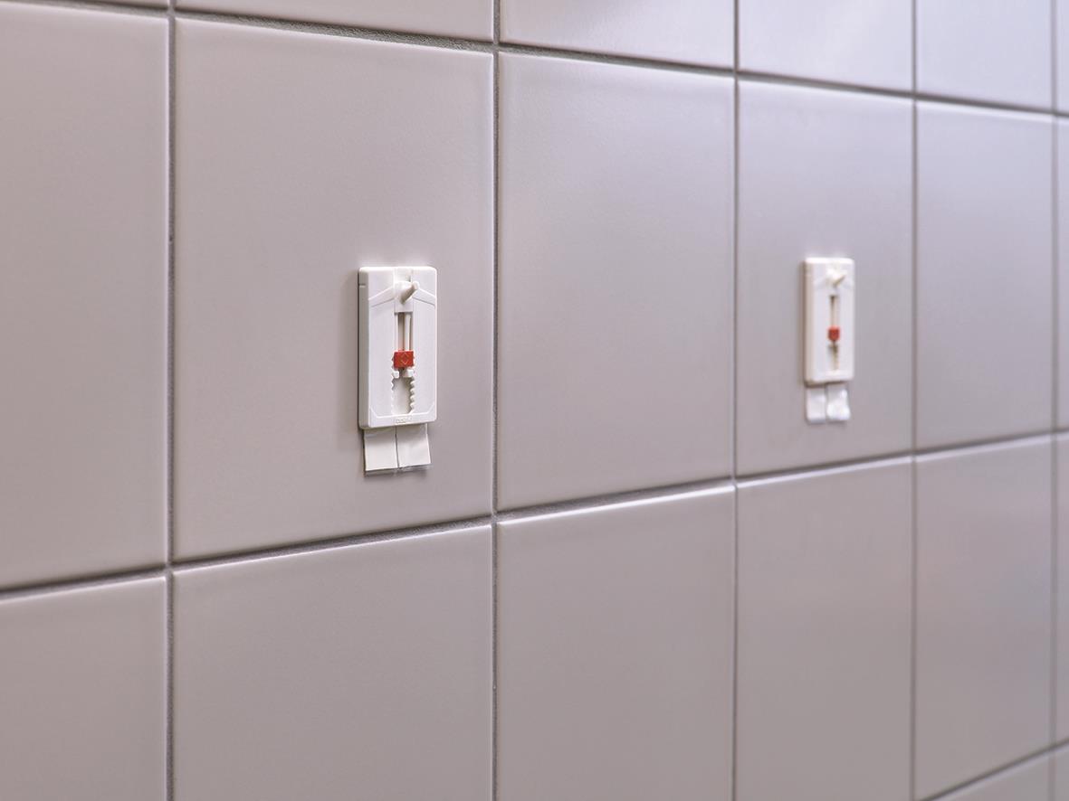 Två självhäftande spik Tesa Powerstrips på kakelvägg