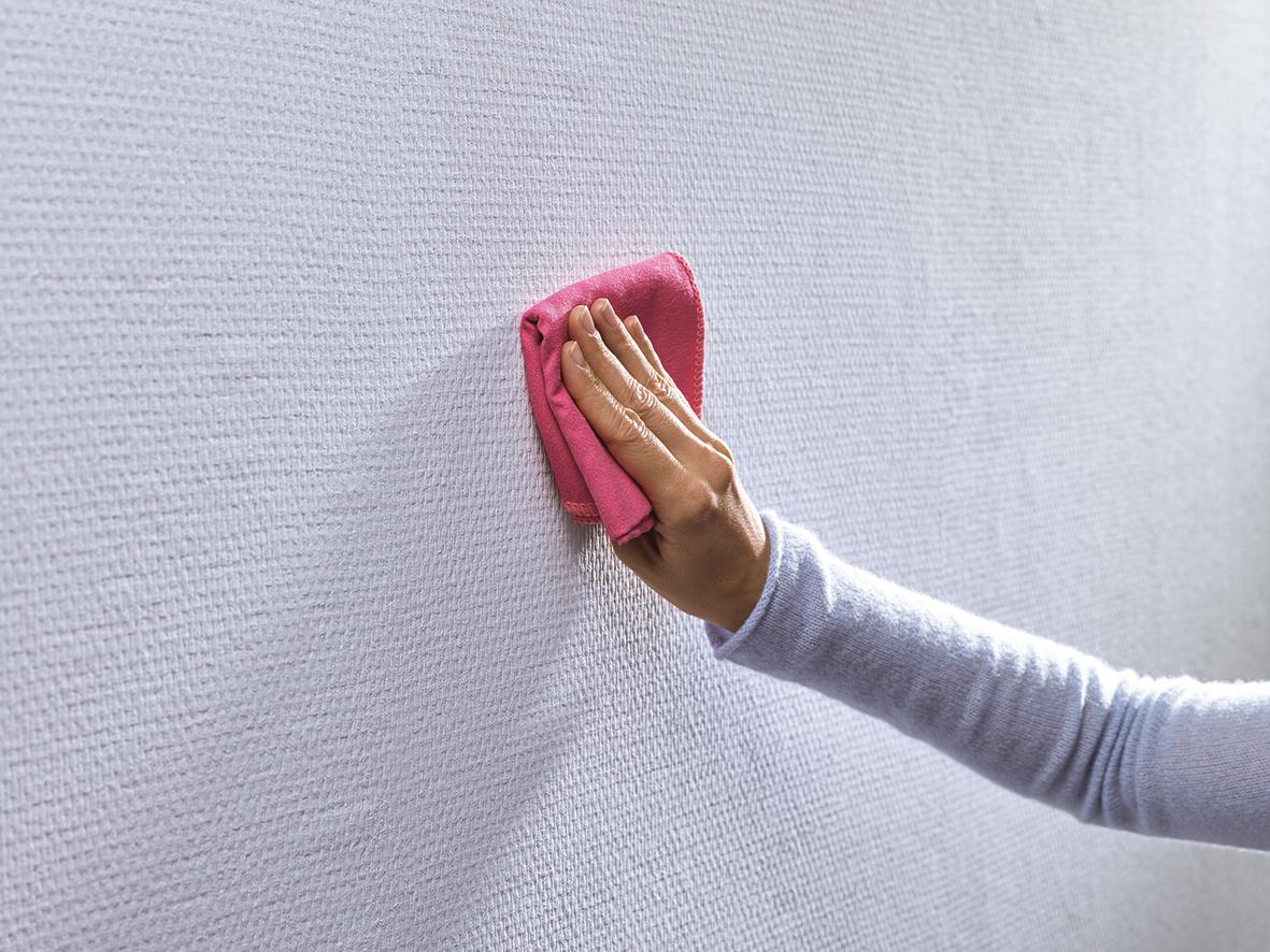 Person som använder en rosa trasa för att torka en vägg