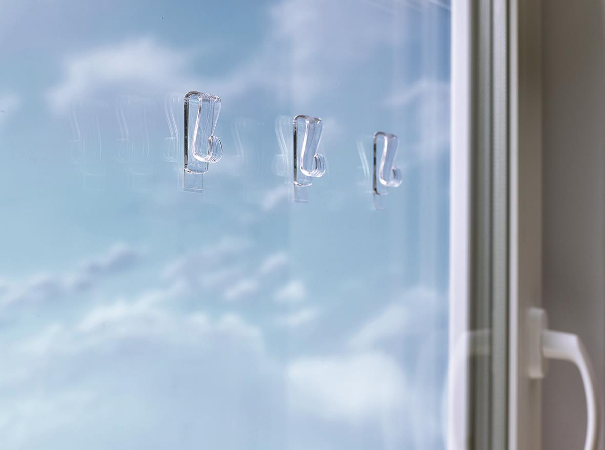 Tre transparenta självhäftande krokar på fönstret