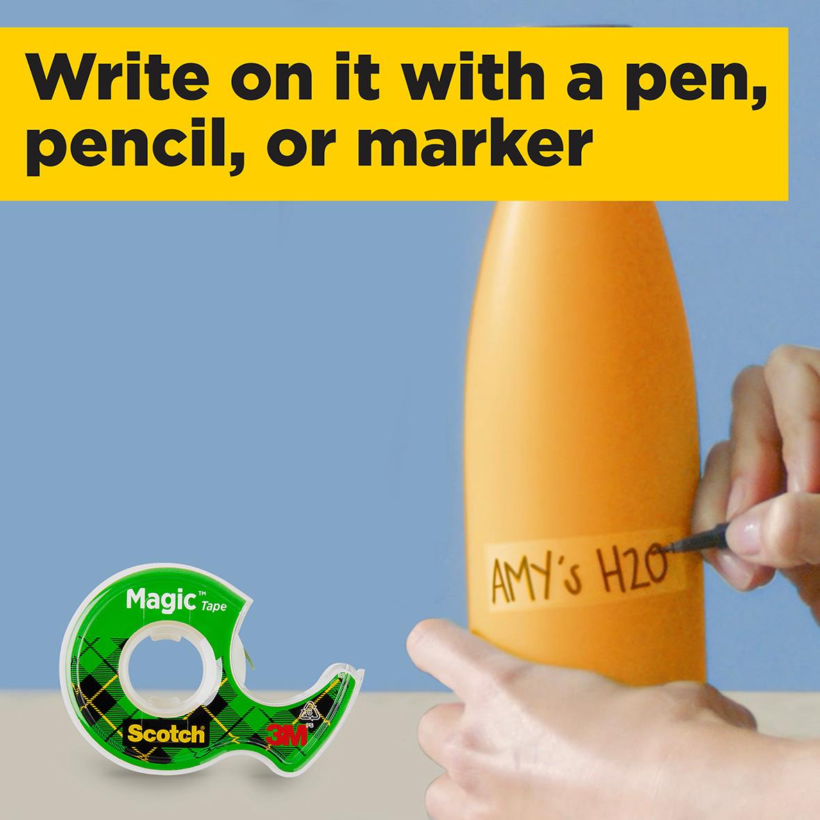 Person håller i Scotch Magic tejp med hållare, omgiven av papper, gem och penna på ett skrivbord