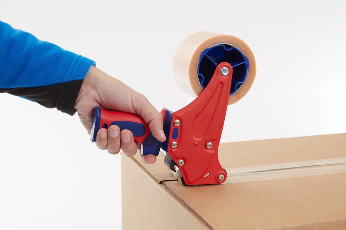 Person använder en handhållen tejpare för att fästa packtejp på en kartong