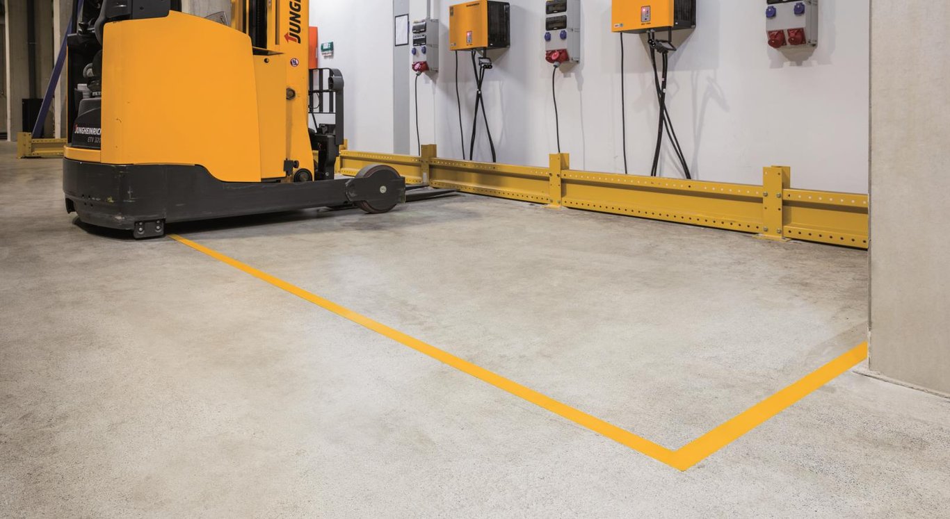 Golvtejp i gul färg markerar en avgränsning på betonggolv i industriell miljö