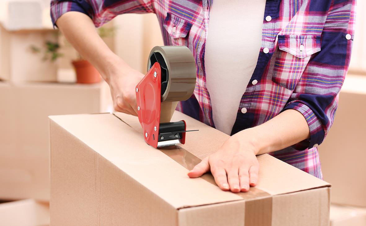 Person använder tejphållare Rapesco med broms för att säkra en kartong