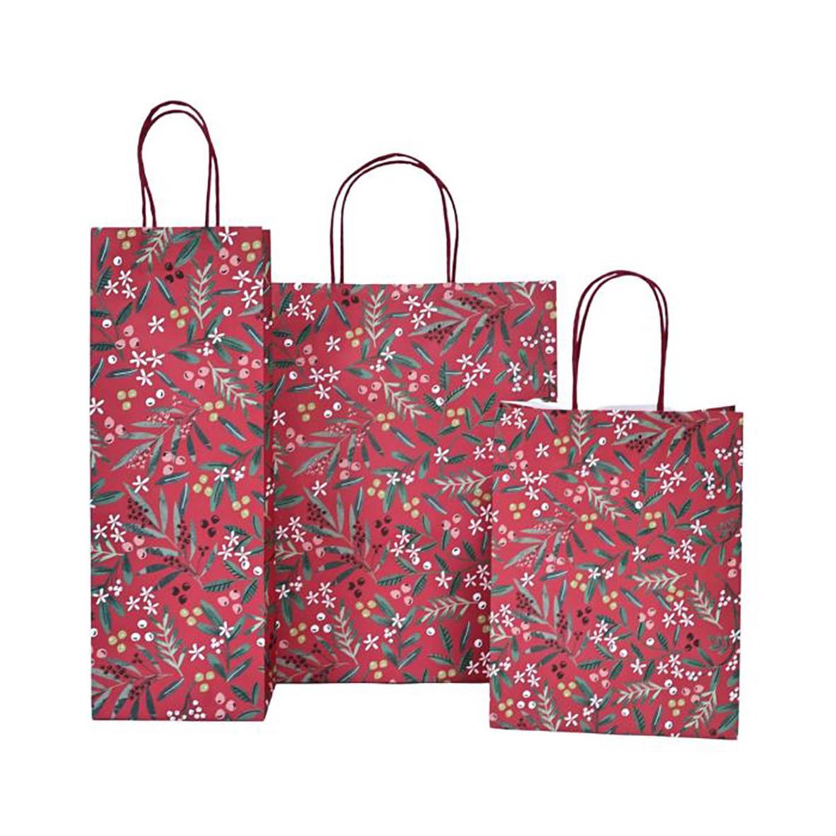 Tre julpåsar med skogsinspirerat mönster i rosa och rött, olika storlekar, med handtag