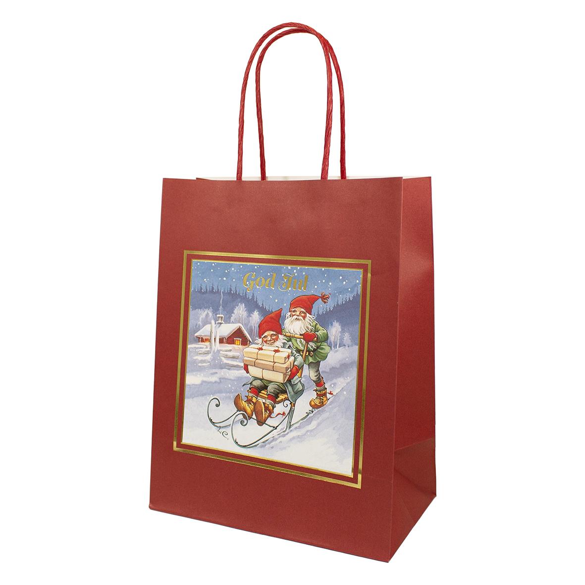 Röd julpåse med handtag och motiv av jultomte på släde i vinterlandskap