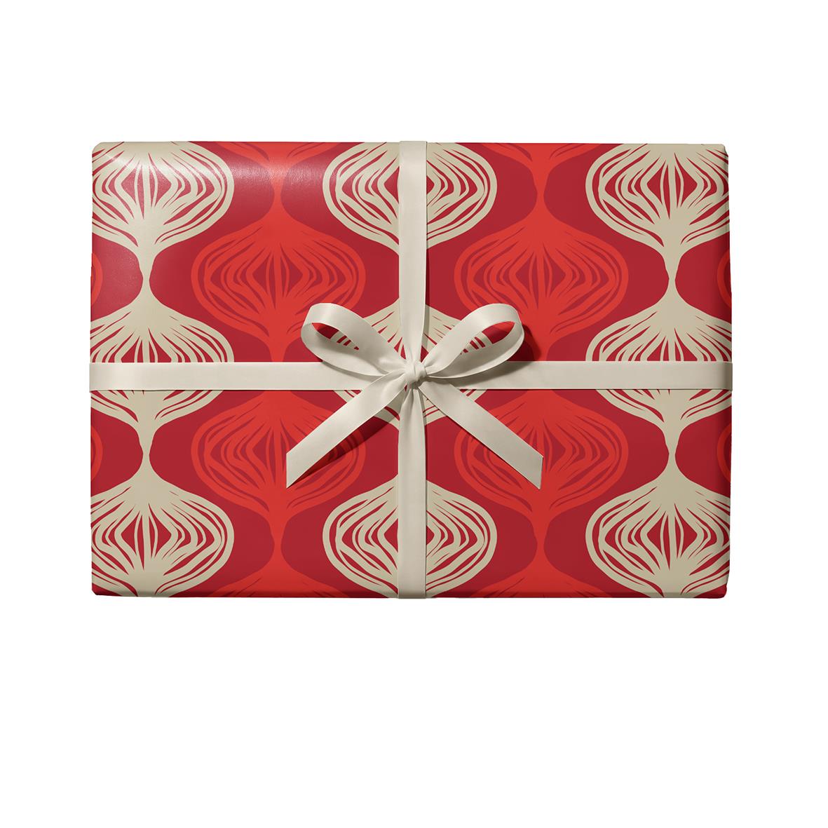 Rött julklappspapper med vitt dekorativt mönster och vit rosett