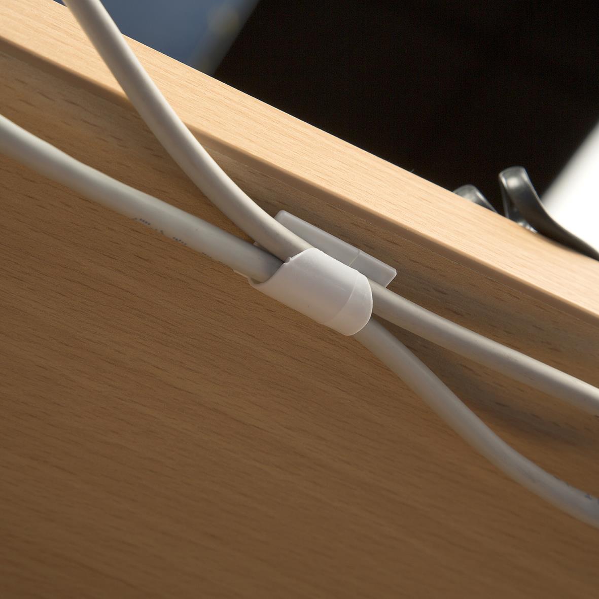 Vit kabelklämma som håller kablar på plats på en träskiva