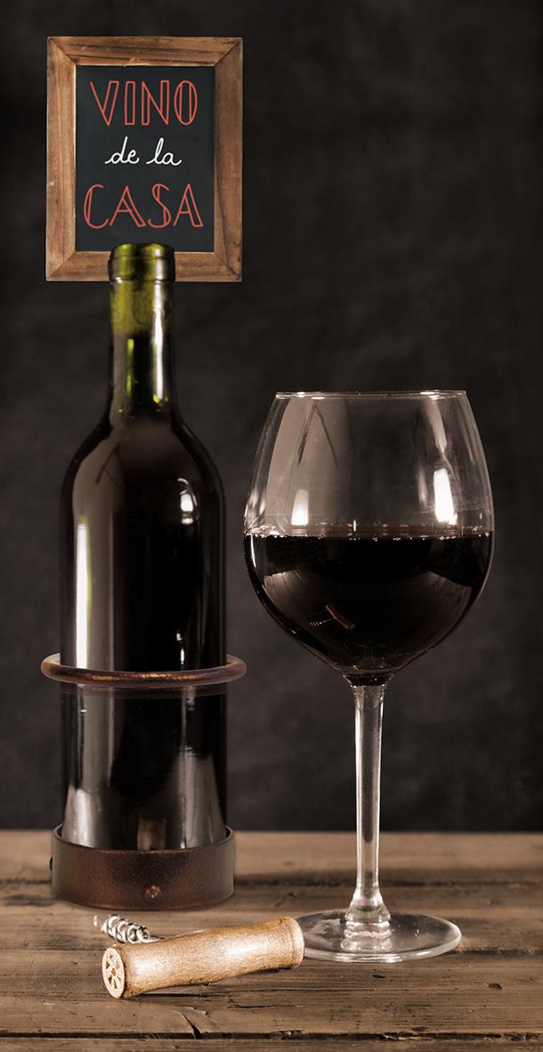 Vinkylare med vinflaska och glas på träbord, griffeltavla med text VINO de la CASA i bakgrunden