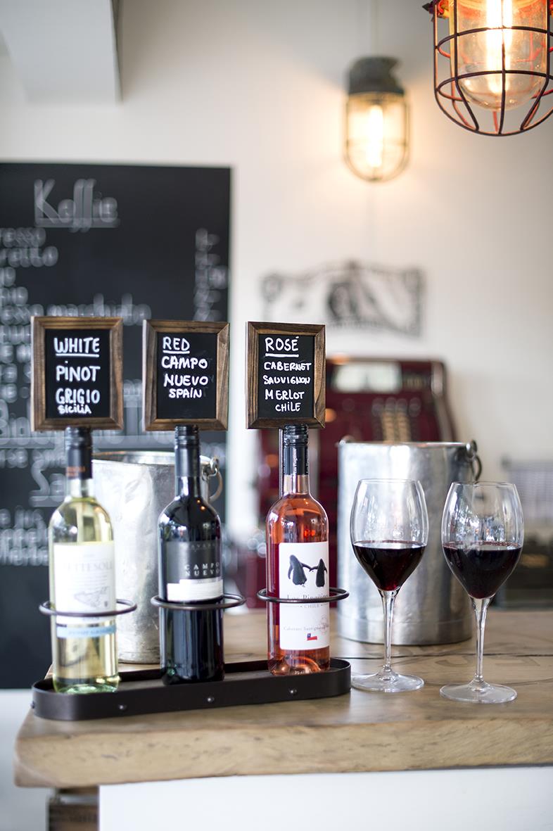 Säkerhetsdisplay med tre flaskor och griffeltavla för etiketter, 45x11cm, i ett café eller bar.