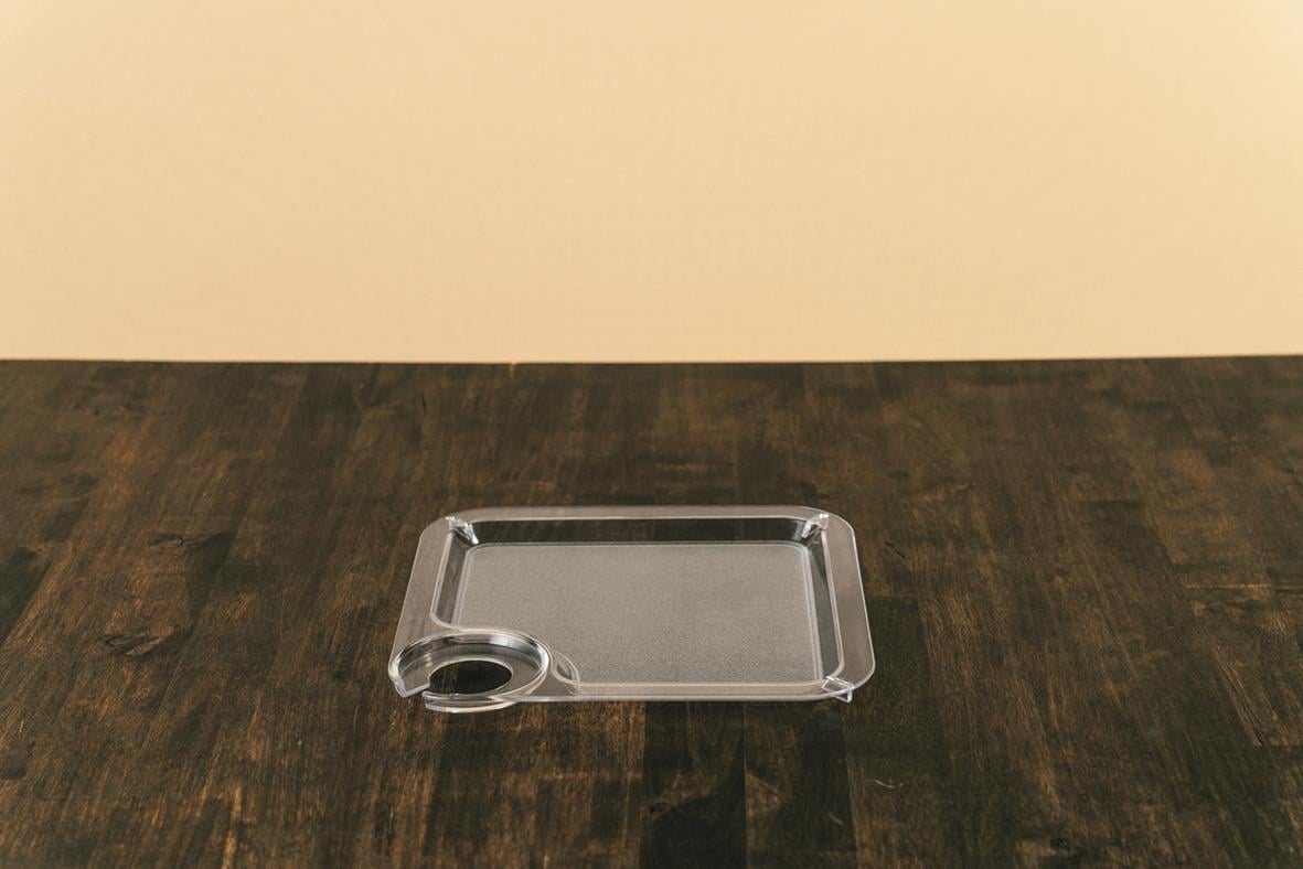 Tydlig bild av en klar plastpartytallrik med hållare för glas på ett mörkt bord