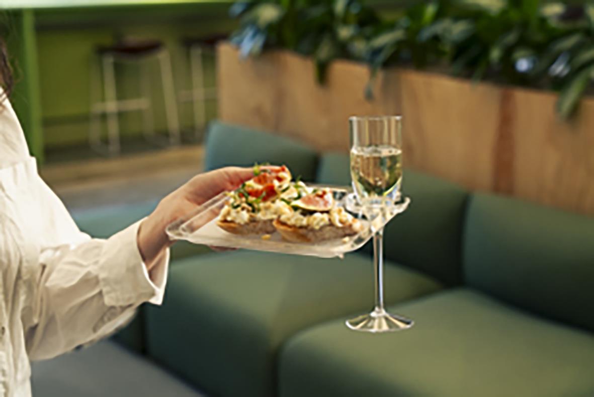 Person håller en tallrik med mat och ett glas vin på en festlig tillställning