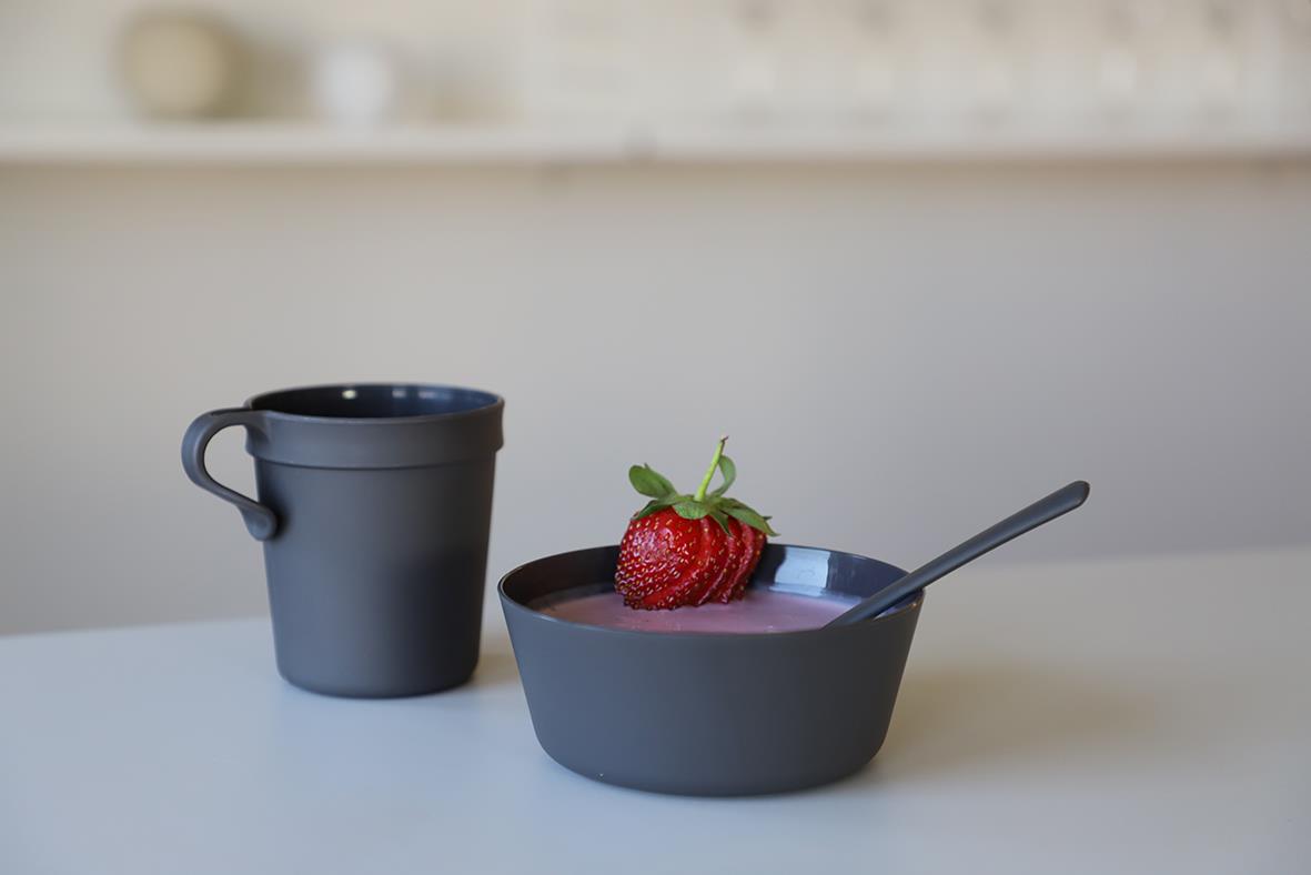 Grå Abena återanvändbar mugg och skål med jordgubbar och sked på ett köksbord