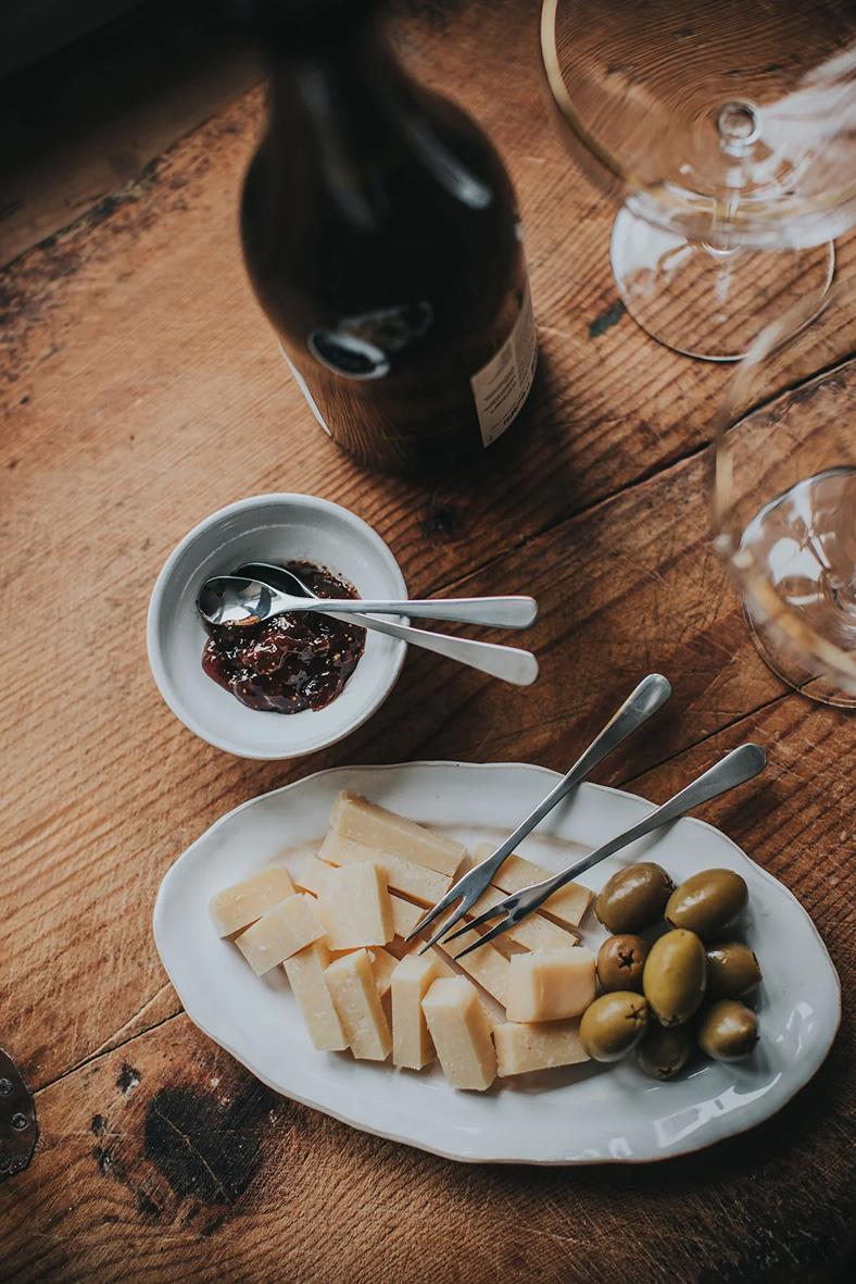 Ost, oliver, marmelad och vin på träbord med glas och vinflaska