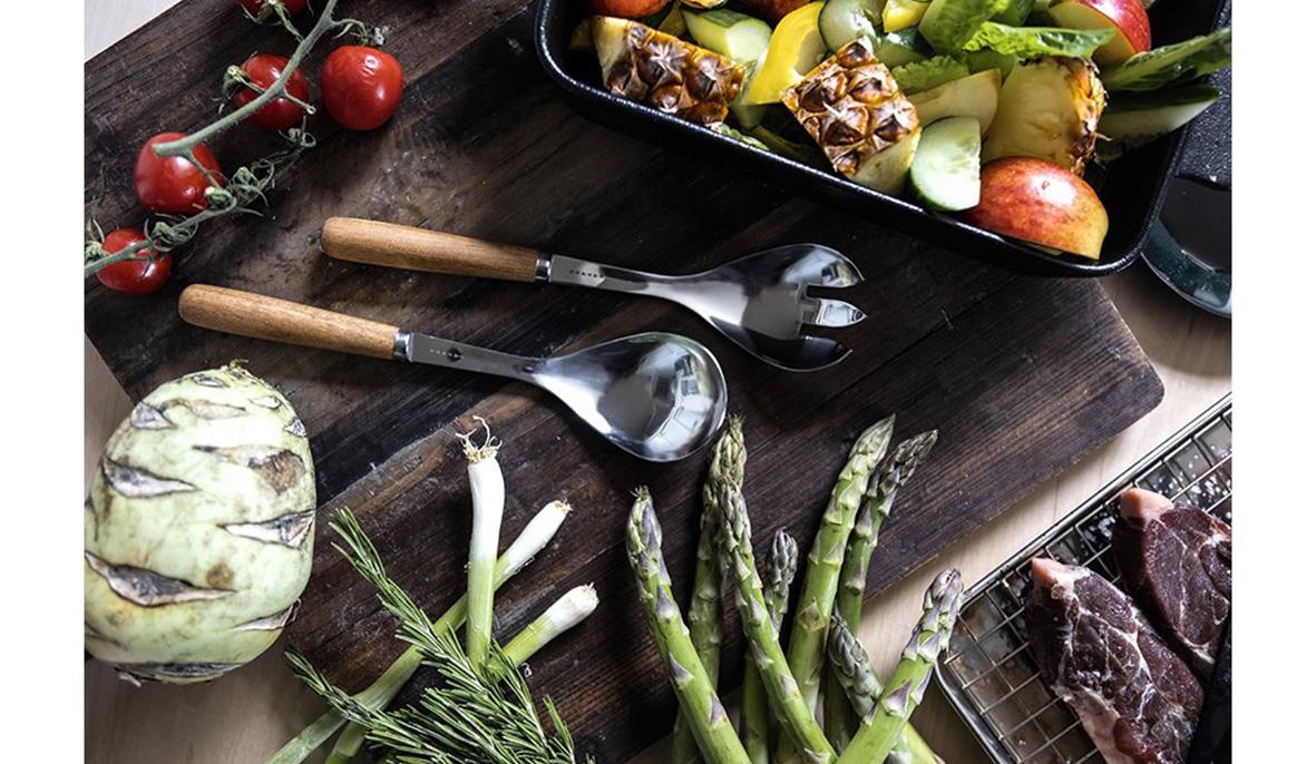 Salladsbestick Satake Shiro med trähandtag, omgiven av grönsaker och kött på träskärbräda