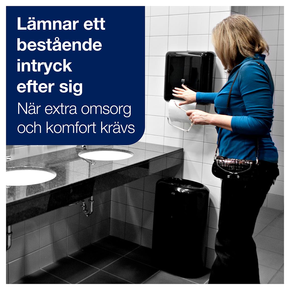 Kvinna i badrum använder pappershanddukshållare för handdukar