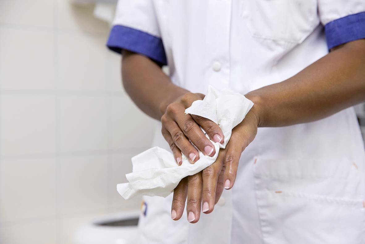 Person torkar händer med pappershandduk i kök eller badrum