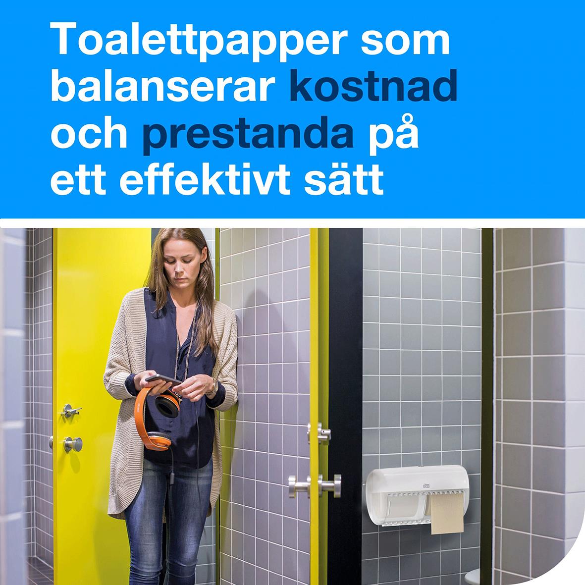 Kvinna i toalettutrymme med Tork T4 Advanced toalettpapper på vägg