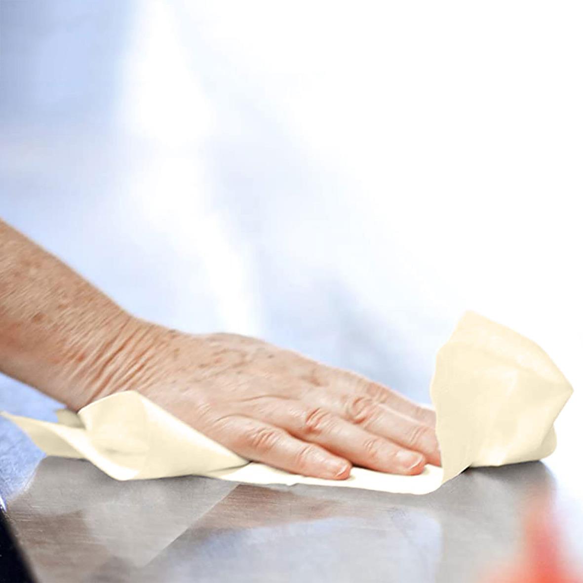 Person torkar en yta med en gul pappershandduk