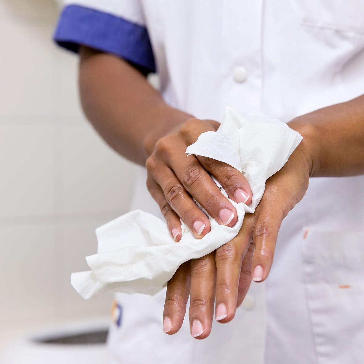 Person torkar händer med vit Tork W4 Plus papper, 32,4x38,5cm