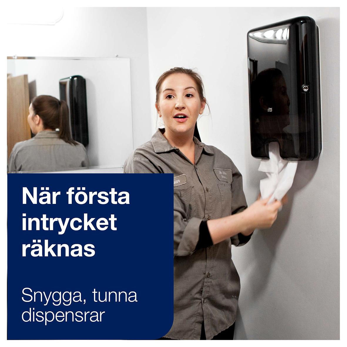Kvinna torkar händerna med svart pappershandduksdispenser i ett badrum eller kök