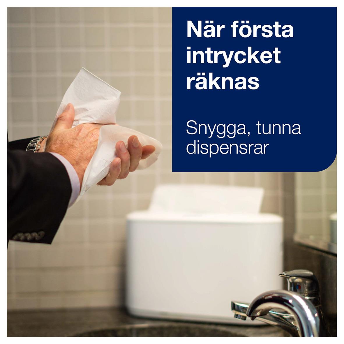 Person som använder en vit pappershandduk från en fristående dispenser i ett badrum