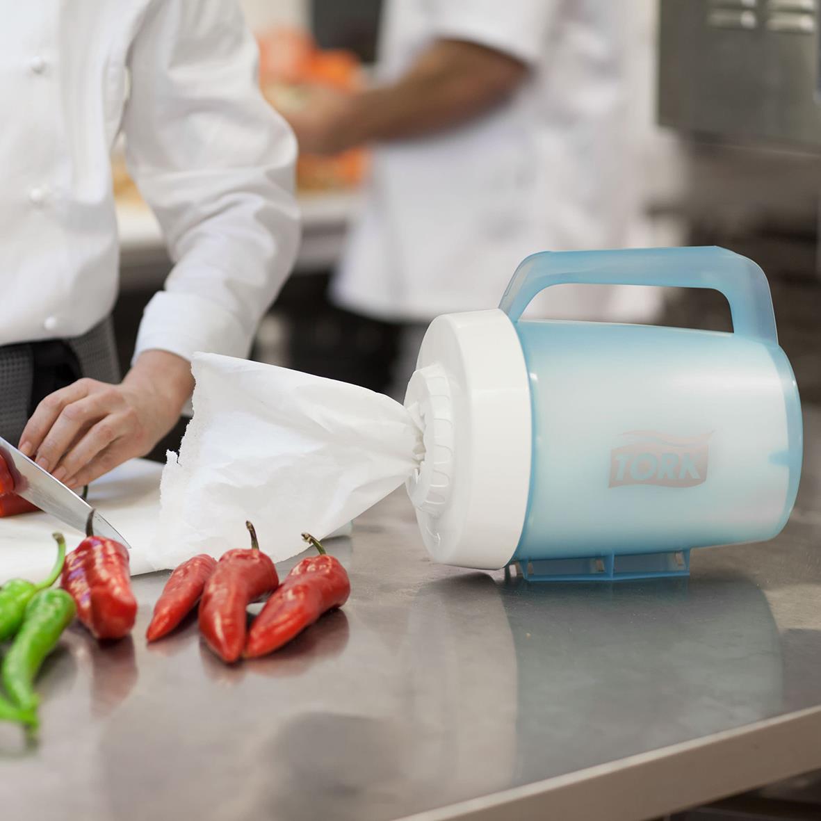 Portabel dispenser för torkrulle på köksbänk med chilipeppar i förgrunden