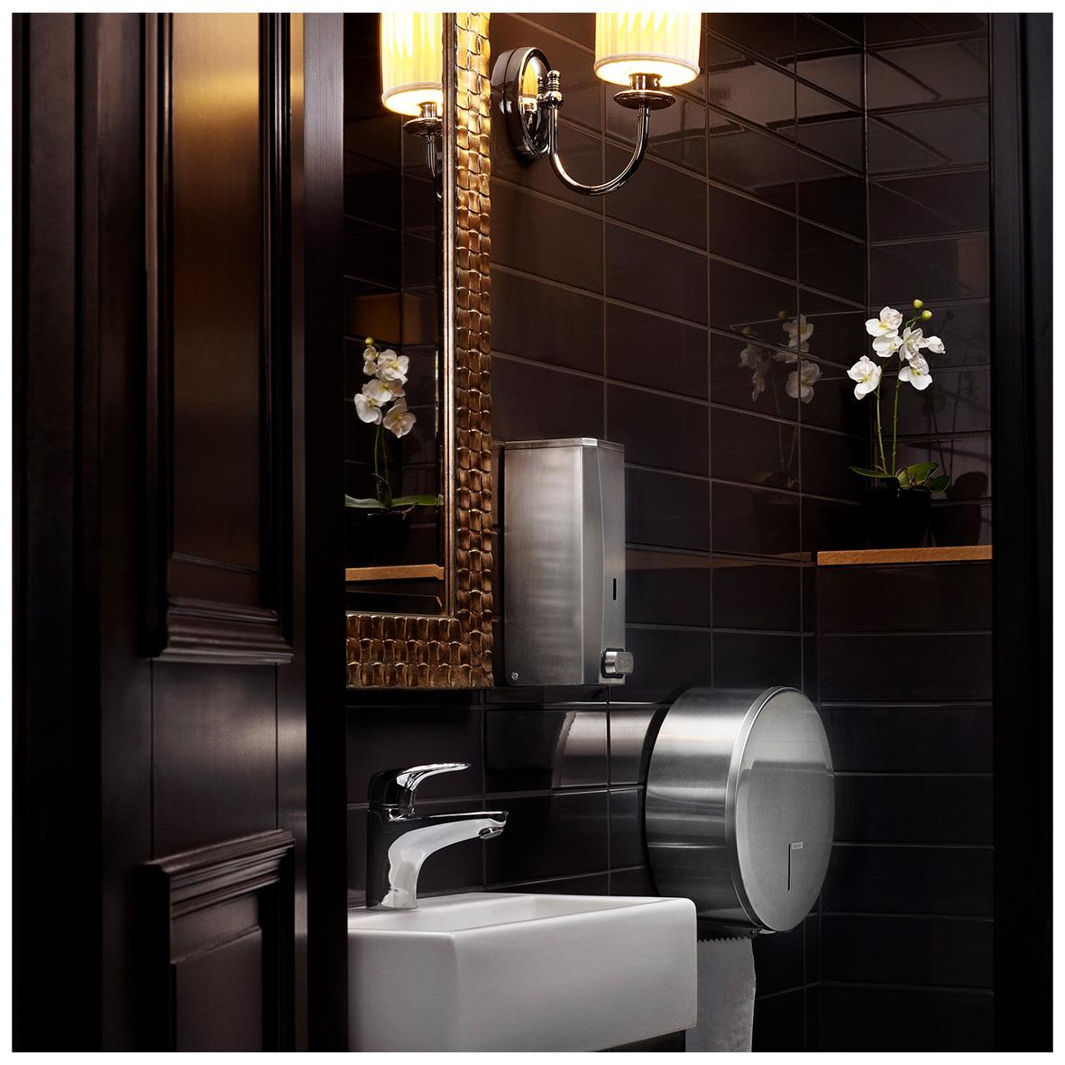 Dispenser för toalettpapper Katrin Gigant S i borstat stål på mörk vägg