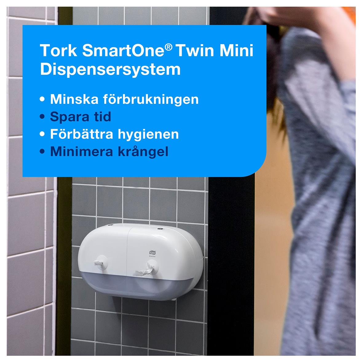 Vit Tork SmartOne Twin Mini dispenser för toalettpapper monterad på vägg med informationsetikett