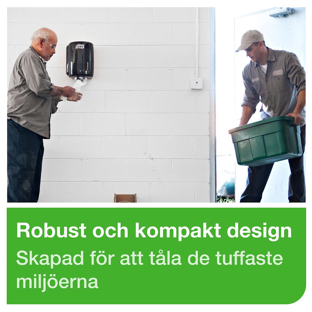 Två personer hanterar en dispenser för Torkrulle Tork W2 Maxi röd/svart, monterad på vit vägg, med en grön informationsruta längst ned.