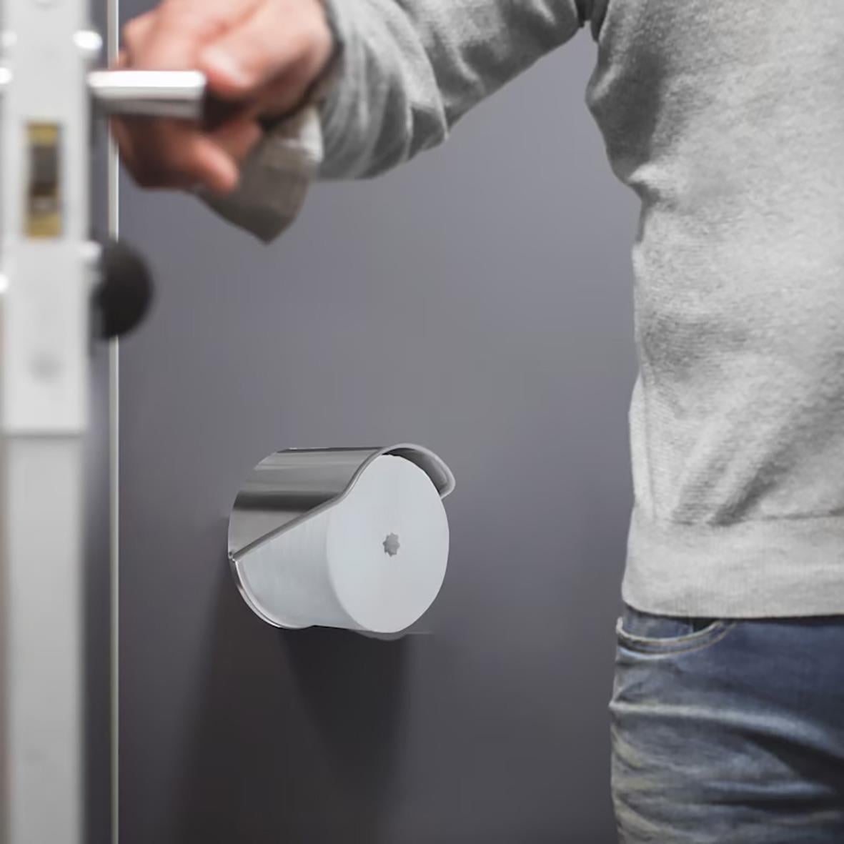 Person som använder dispenser för toalettpapper Tork T7 Coreless i rostfritt, monterad på vägg