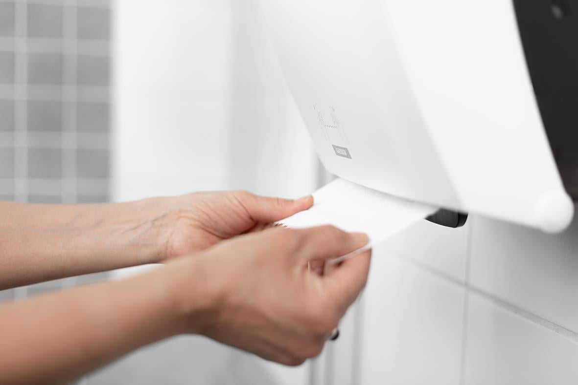 Person som tar ett papper från Katrin System M2 vit pappershanddukspressare