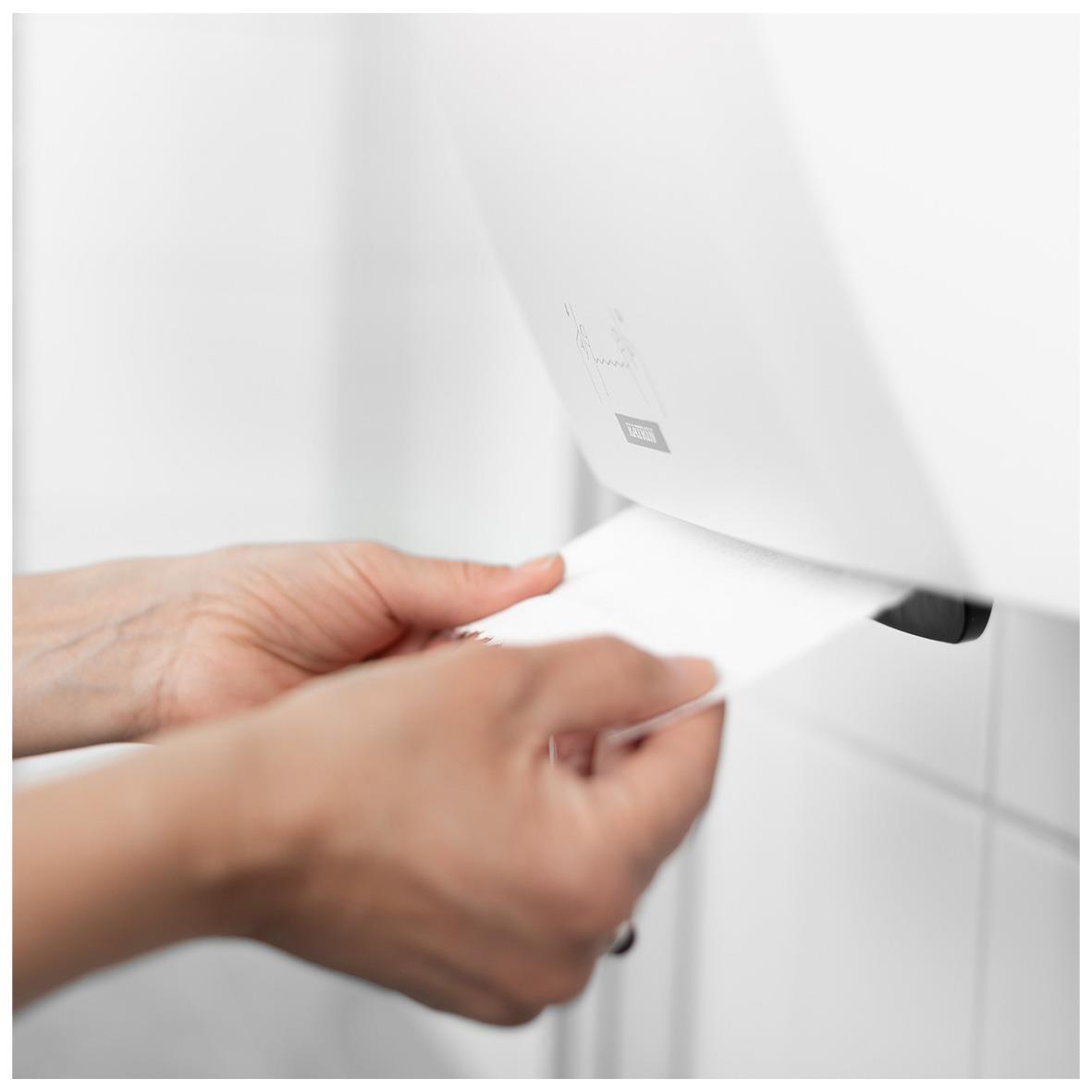 Person som tar ett papper från Katrin System M2 svart pappershanddukdispenser