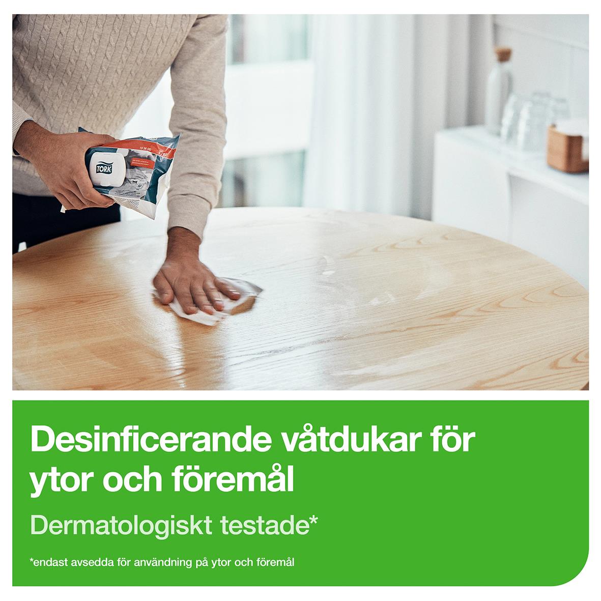 Person som desinfekterar en träbord med våtdisinfektionsservett