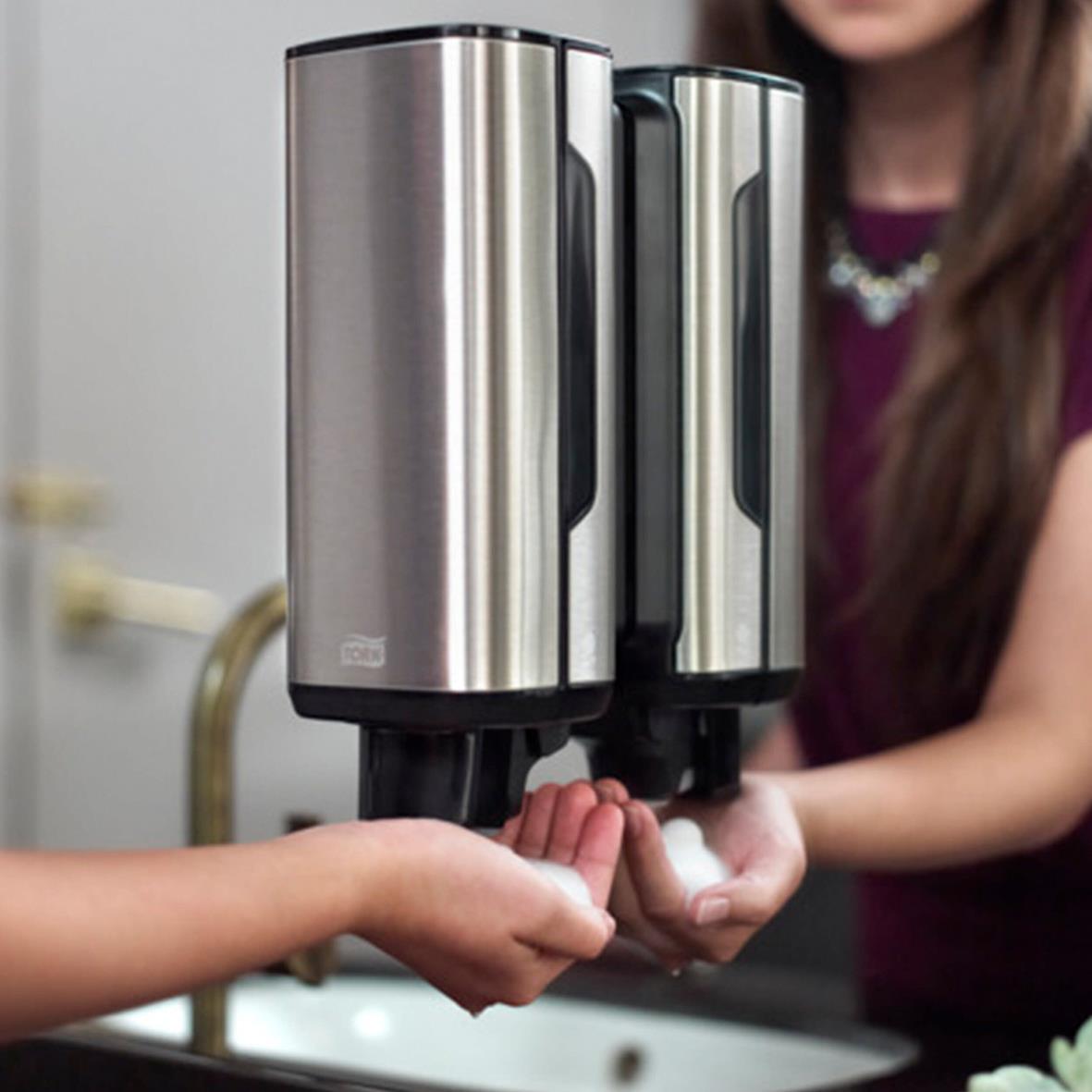 Två personer använder skumtvål Tork S4 Sensitive 1L från dispenser