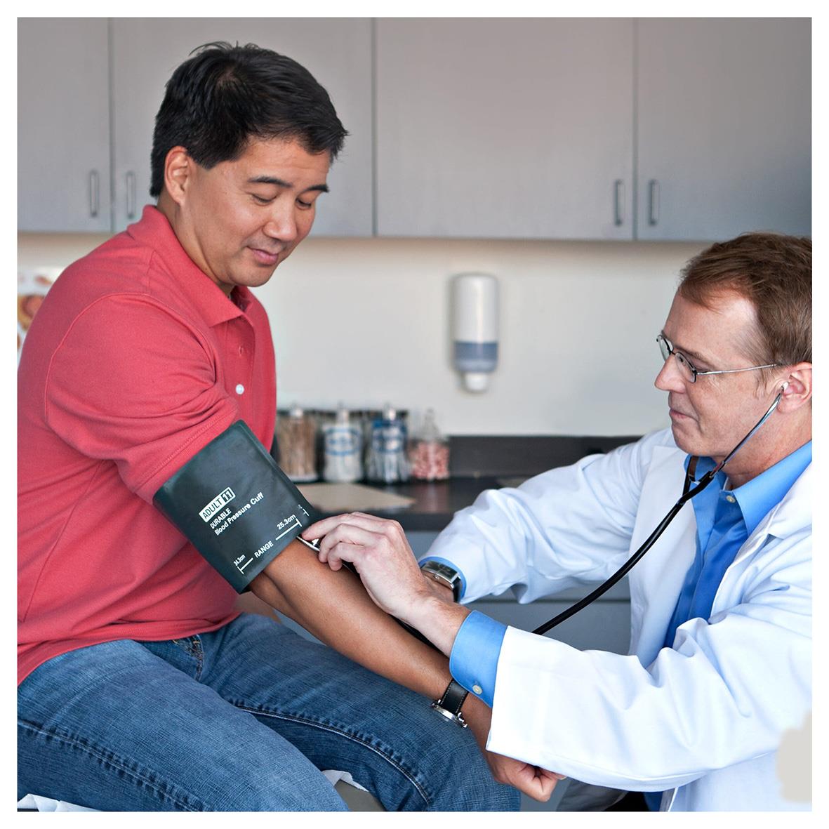 Läkare mäter blodtryck på patient i klinik, bakgrund med medicinsk utrustning och skåp