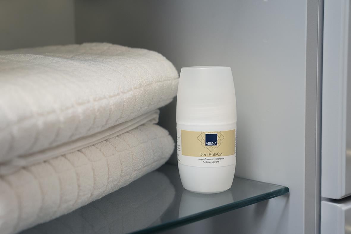 Deodorant Abena Roll-On Oparfymerad 50ml på en hylla bredvid vita handdukar