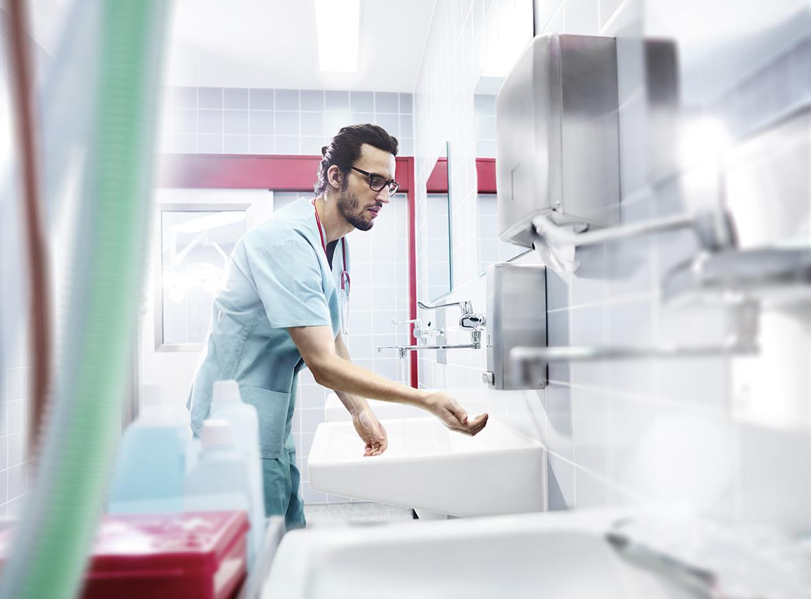 Person som fyller en Katrin tvål dispenser i ett kök eller badrum med stålfinish