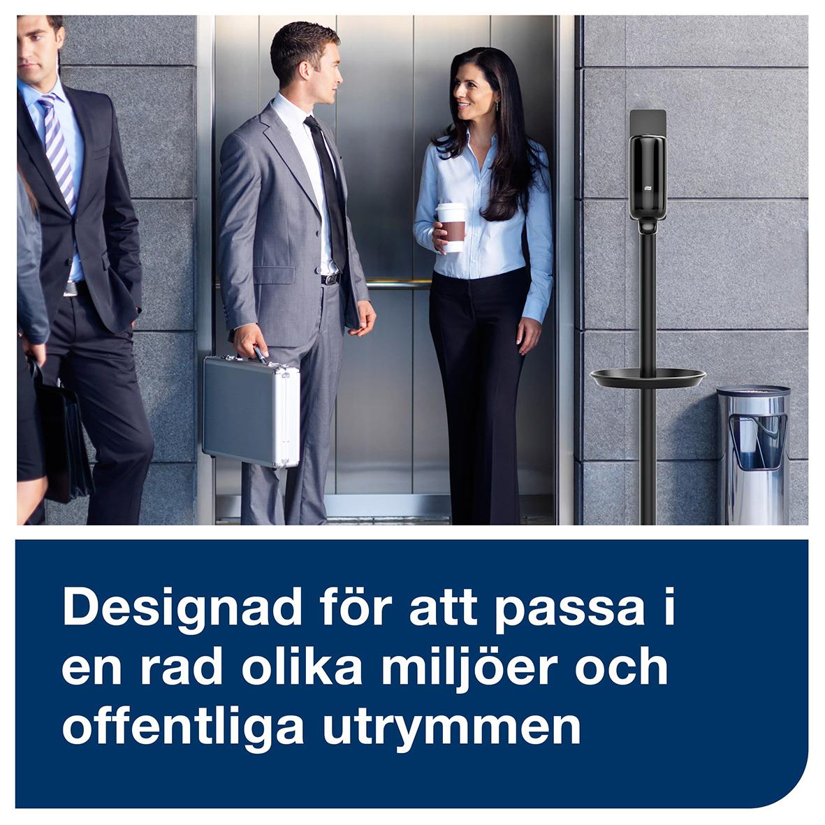 Golvstativ Tork utan dispenser med rund stolpe placerad utanför en hiss, tre personer i affärskläder samt en väggmonterad telefon